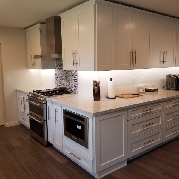 Bright & Modern Kitchen Renovation by Five40 Remodeling LLC in Mesa, AZ A bright, modern kitchen featuring white shaker-style cabinetry, light countertops, a mix of subway tile and patterned tile backsplash, stainless steel appliances, and wood-look flooring.